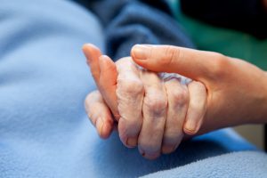 A young hand touches and holds an old wrinkled hand